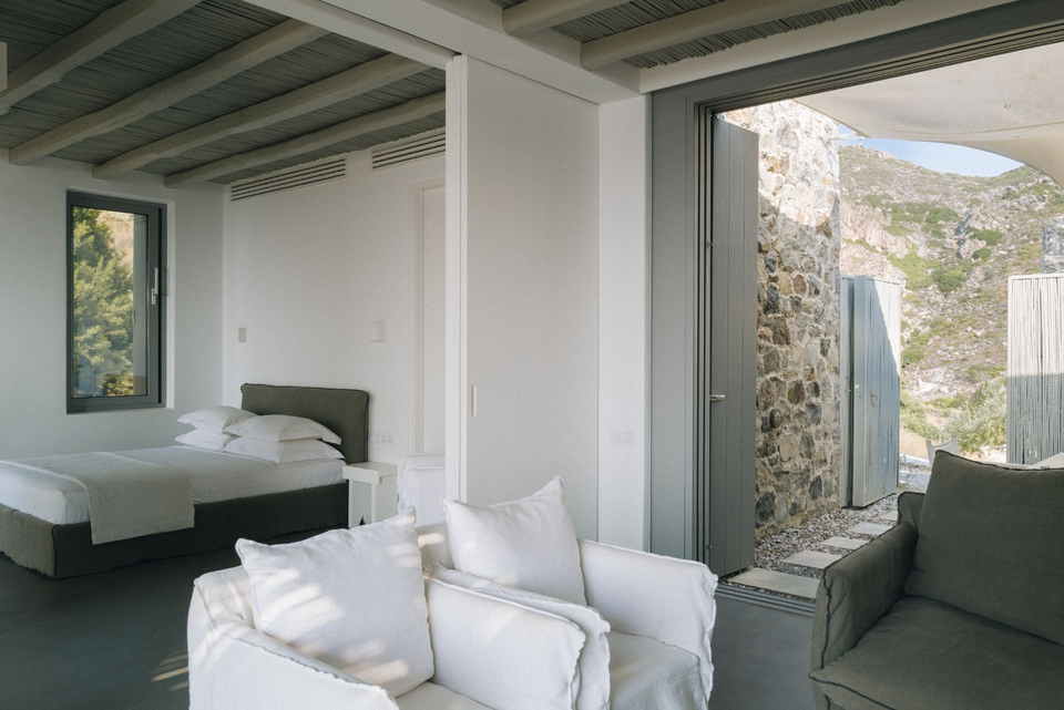 Minimalist luxury hotel bedroom suite with stone wall details and natural light