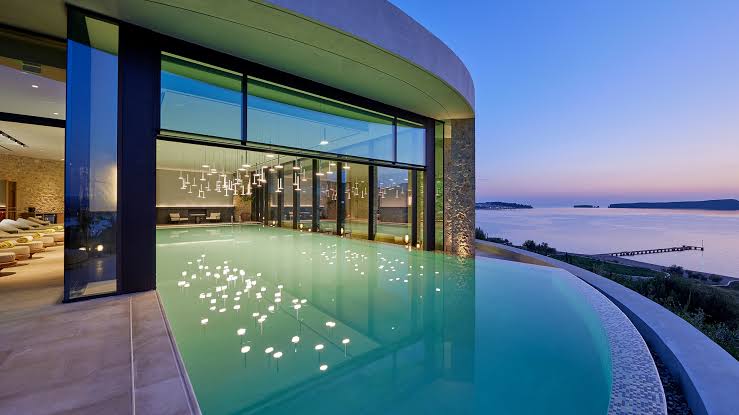 A stunning, modern infinity pool and luxury lounging area overlooking the sea at the Mandarin Oriental resort in Costa Navarino