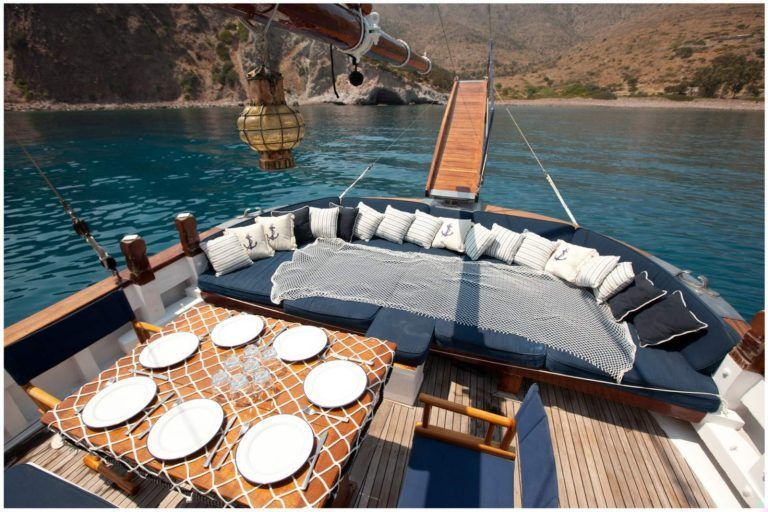 Wooden luxury yacht lounge deck prepared for private dining in Milos bay
