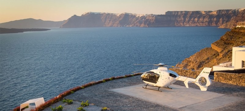 Private helicopter landing at a Santorini villa helipad overlooking the caldera
